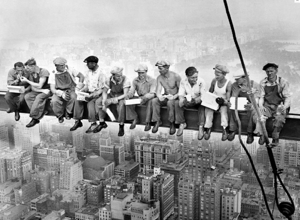 Construction workers having lunch atop skyscraper in building crossbeam in New York