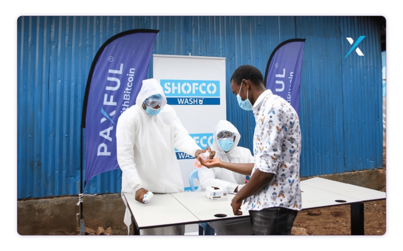 A person sanitizing a man's hands at SHOFCO booth